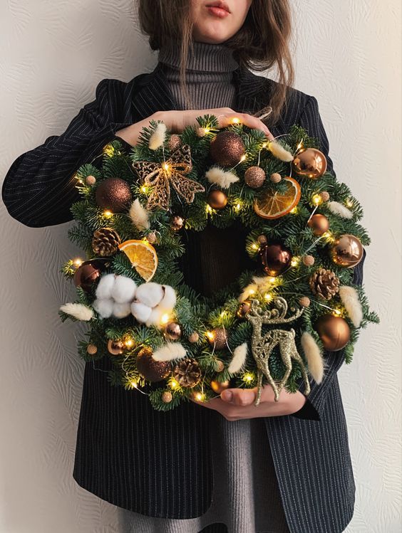 A beautiful holiday wreath made from evergreens, brown ornaments, pine cones, citrus, cotton and lights is wow