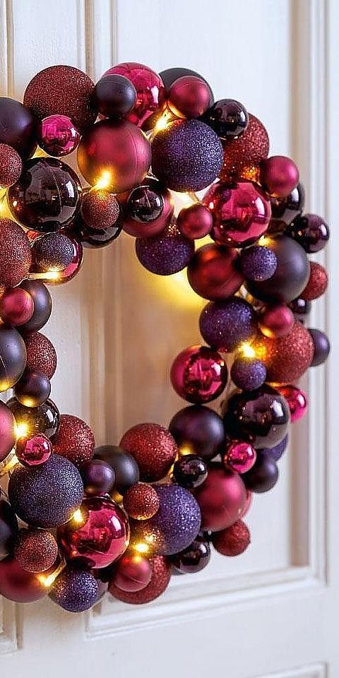 A colorful Christmas wreath full of ornaments in fuchsia, purple, violet colors and with lights is wow