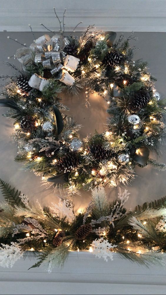 a glamorous Christmas wreath with evergreens, pine cones, silver leaves and bows as well as lights and branches