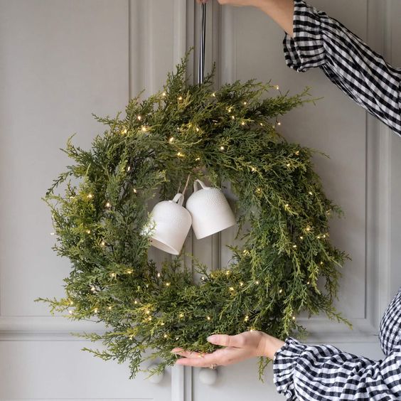 A green Christmas wreath with lights and large white bells looks fresh and current