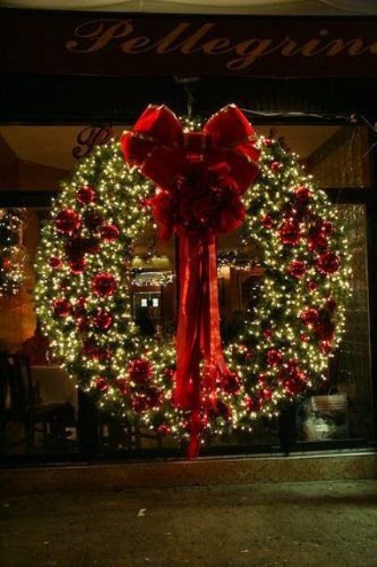 A luxurious Christmas wreath made of evergreens, red ornaments and a big red bow is amazing