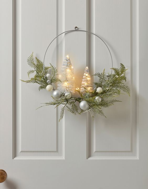 A modern Christmas wreath with greenery, silver baubles, and lighted bottlebrush trees is a cool idea for the holidays