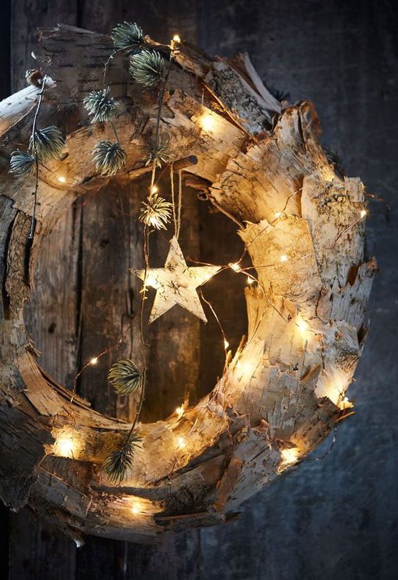 A rustic Christmas wreath made of bark, lights, bark stars and greenery is a cool and unusual decorating solution