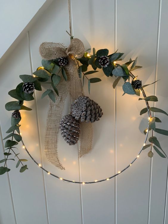 A rustic Christmas wreath with lights, greenery, pine cones and a burlap bow is fantastic