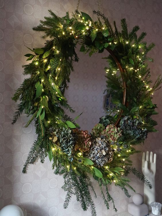 A textured Christmas wreath with evergreens, foliage, lights and flowers is a stylish decoration idea