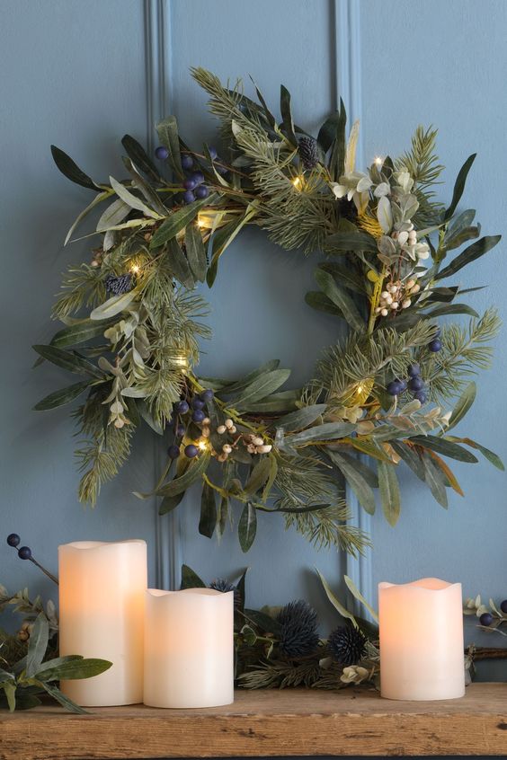 A textured green Christmas wreath with white and blueberries and lights is cool for a natural decoration