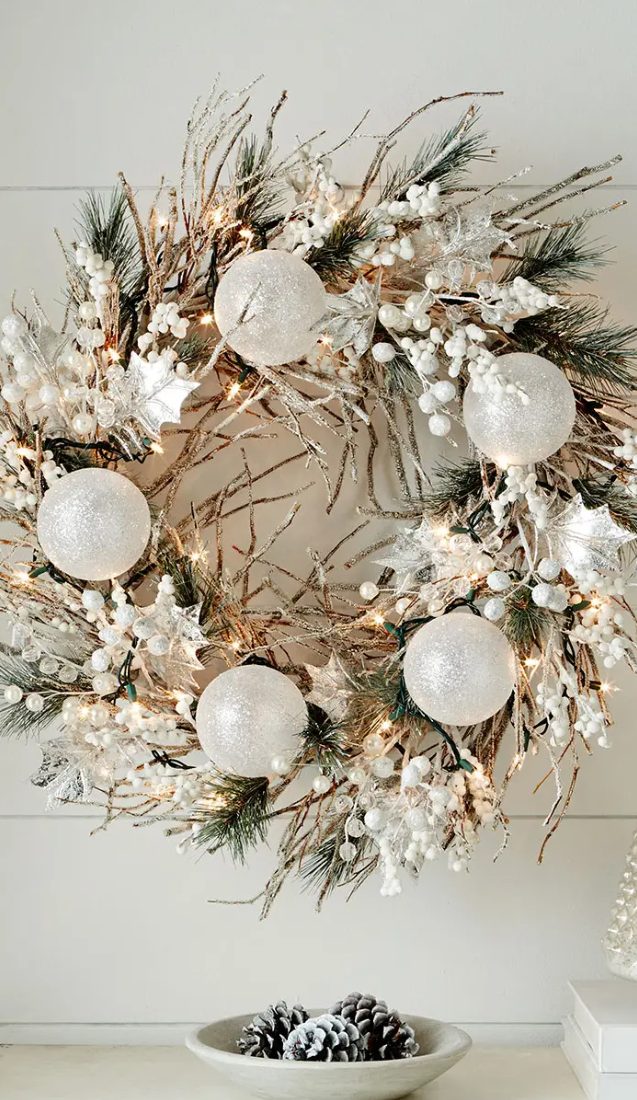 an ethereal Christmas wreath with branches, evergreens, white ornaments, elves, berries and lights