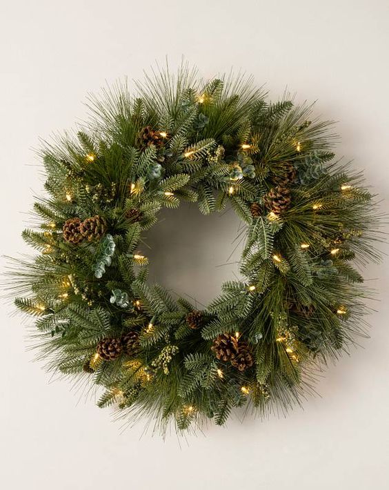 An evergreen Christmas wreath with pine cones and lights is a cool decoration for almost any room