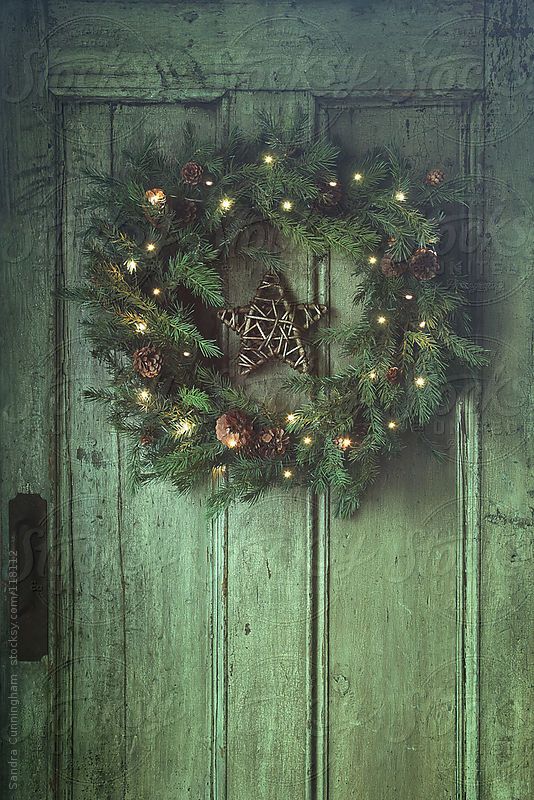 An evergreen Christmas wreath with pine cones and lights and a twig star is a cool rustic decoration for the holidays