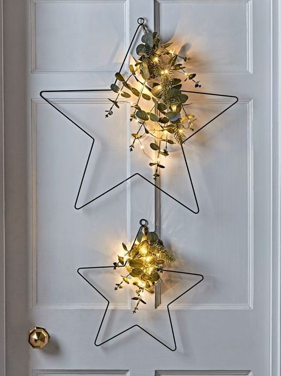 Star-shaped metal Christmas wreaths with evergreens, eucalyptus and lights are a great decoration idea for a Scandinavian or modern room