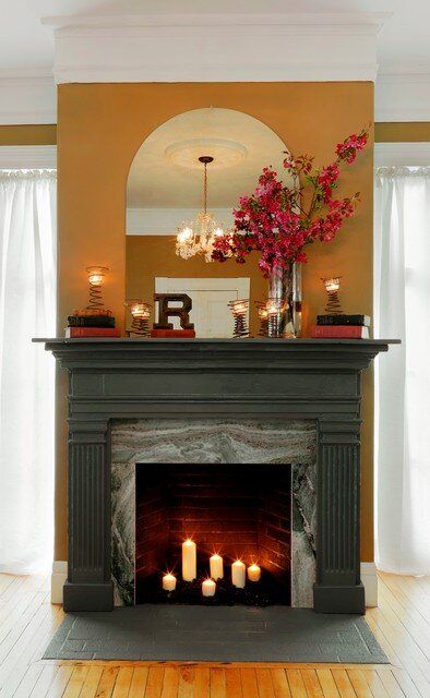 A non-working fireplace with candles, books, bold flowers and a monogram on the mantel is beautiful