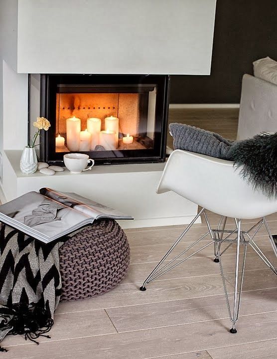 A Scandinavian room with a built-in fireplace and pillar candles inside is a creative and cozy corner