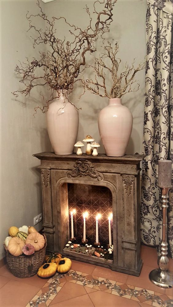 A vintage fireplace with moss, mushrooms and tall thin candles, branches in pink vases on the mantel