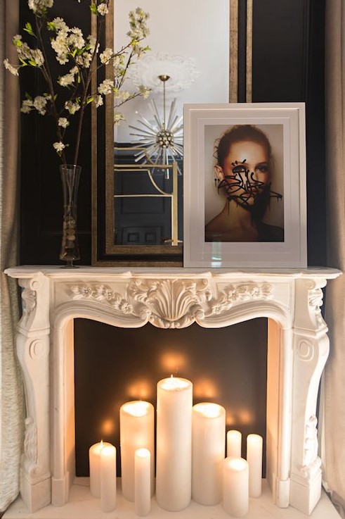 an intricately carved marble mantel filled with lit candles, against a black background that highlights them