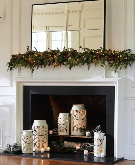 Beautiful white snowflake candle lanterns with candles, pine cones and pine branches for a holiday-ready fireplace