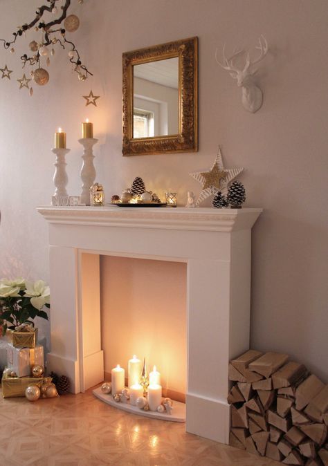 a faux fireplace with white pillar candles, neutral ornaments and stars for a Christmas atmosphere