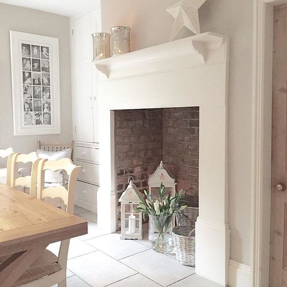 A large non-working fireplace with bricks inside, candle lanterns, flowers and whitewashed baskets is chic