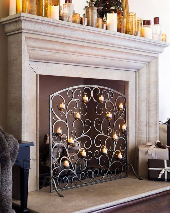 A non-functioning fireplace with firewood and a sophisticated metal screen with lots of candles provide ultimate elegance