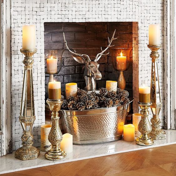 a whimsical fireplace with birch trees, candles all around, a metal bathtub with pine cones and a polished metal deer head