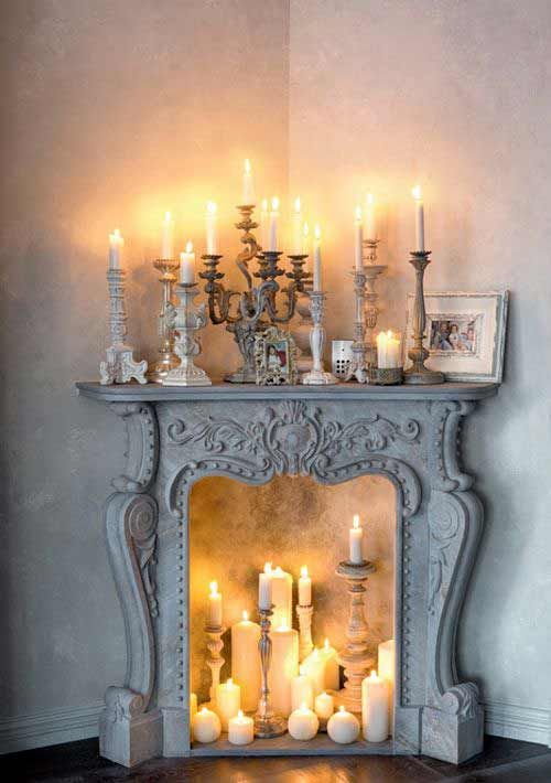 A whitewashed sophisticated fireplace with various candles inside and on the mantel looks beautiful and sets the mood