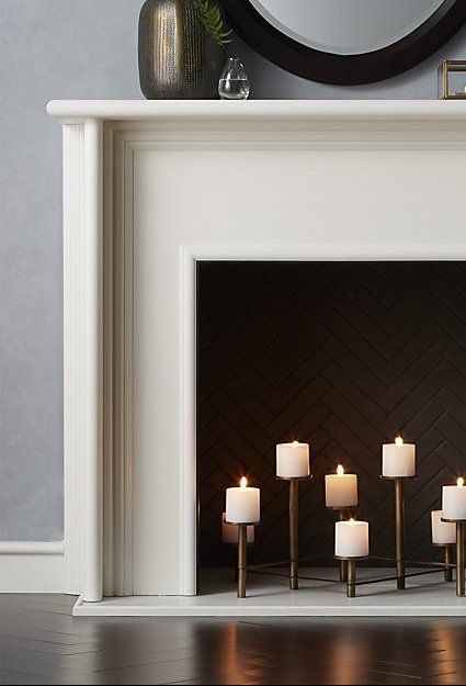 A stylish white fireplace with brick interior and a chic brass candelabra is a cool alternative to an ordinary fire