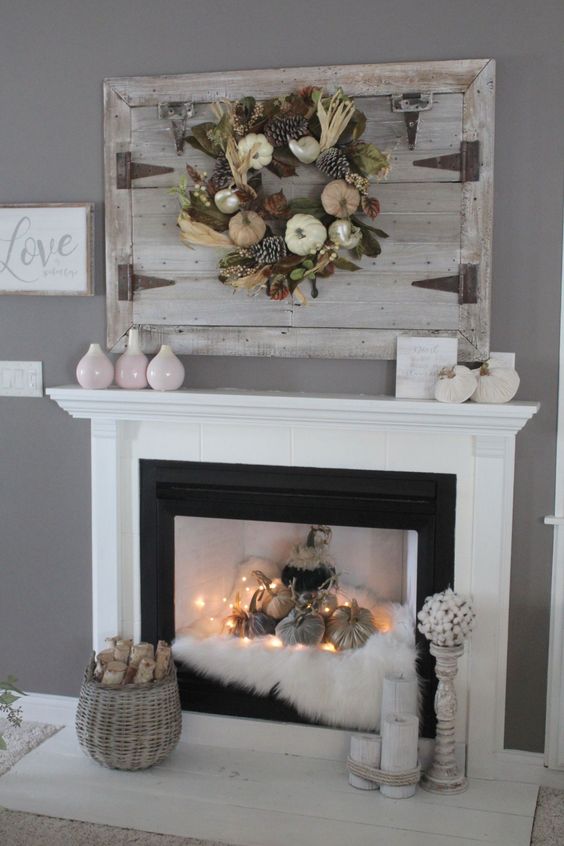 a non-working fireplace with faux fur, fabric pumpkins and lights everywhere and firewood around it