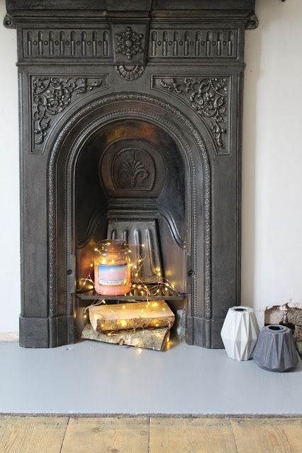 A Victorian fireplace with a large candle, firewood and lights looks modern, fresh and catchy