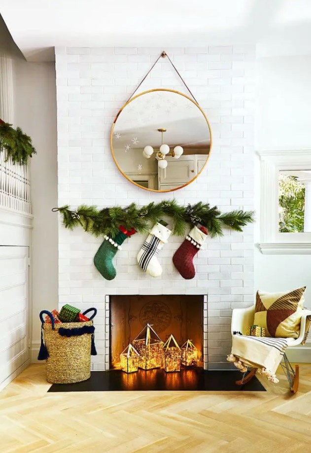 A non-working Christmas-themed fireplace with some stockings hanging above it and lanterns inside