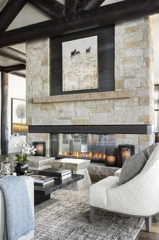 a chalet living room with stone stools, a low marble coffee table and seating and an amazing double-sided stone fireplace