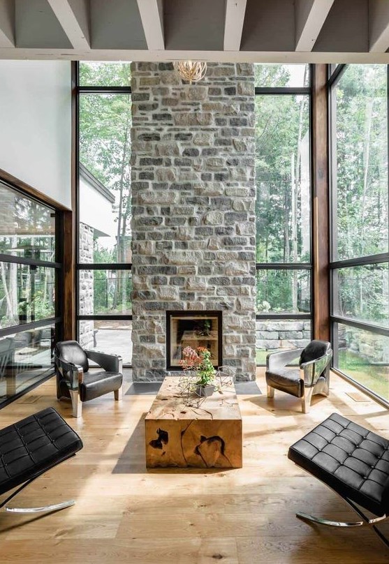a chic, modern living room with a stone fireplace as a centerpiece, black leather armchairs and a wooden table