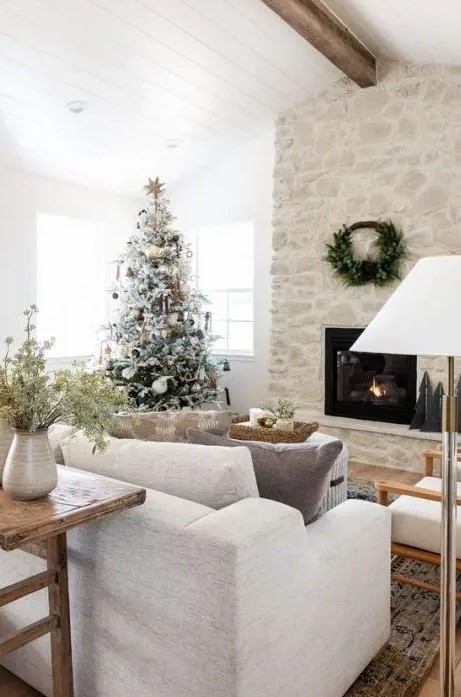 A beautiful fireplace made of whitewashed stones with a wreath above takes up the entire room and looks chic