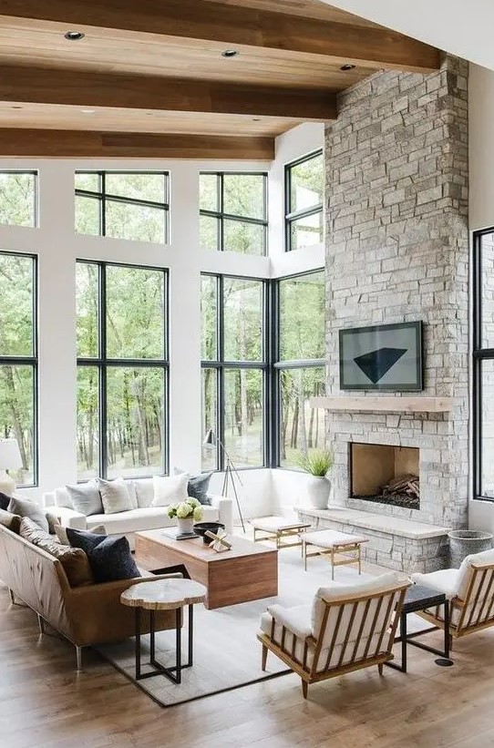 a modern, rustic living room with a stone-clad fireplace, wooden furniture and a leather sofa and comfortable wooden chairs