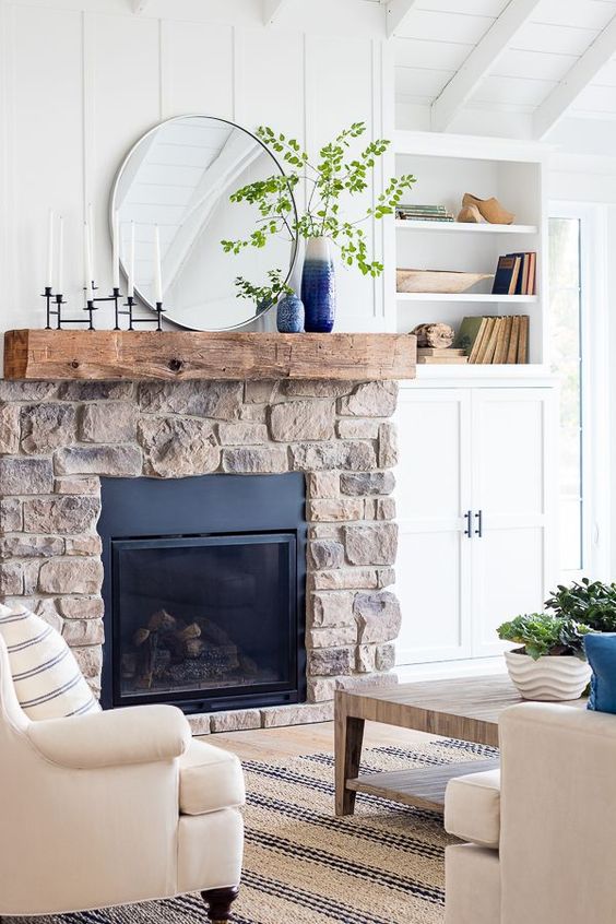 a neutral living room with built-in storage, a stone fireplace, neutral seating and a coffee table