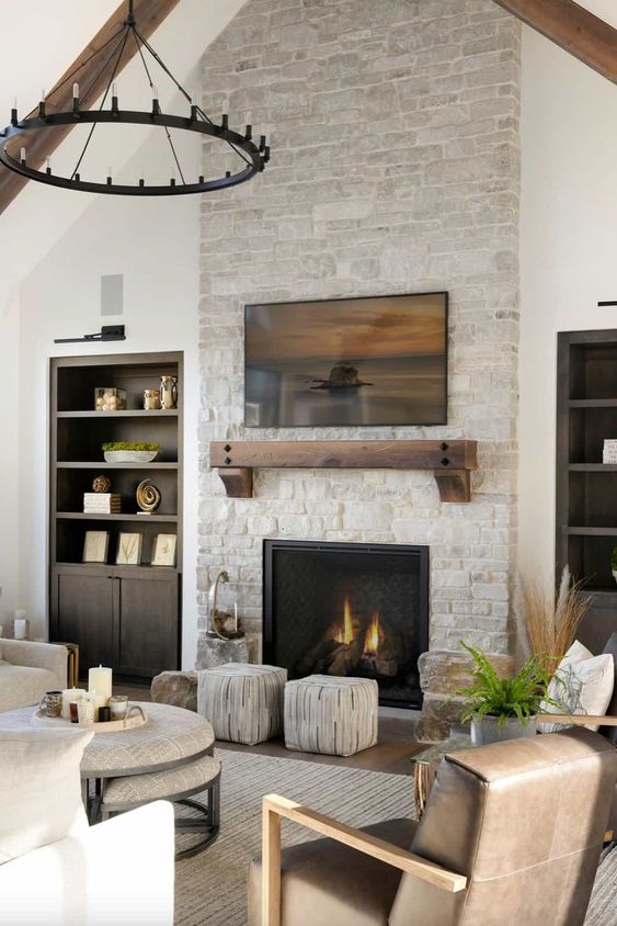 a neutral living room with built-in storage cabinets, a fireplace, a tiered coffee table, stools and some art