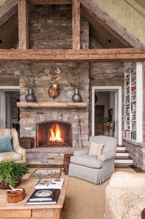 An inviting cabin living room with stone walls and fireplace, exposed beams, a jute rug and vintage furniture
