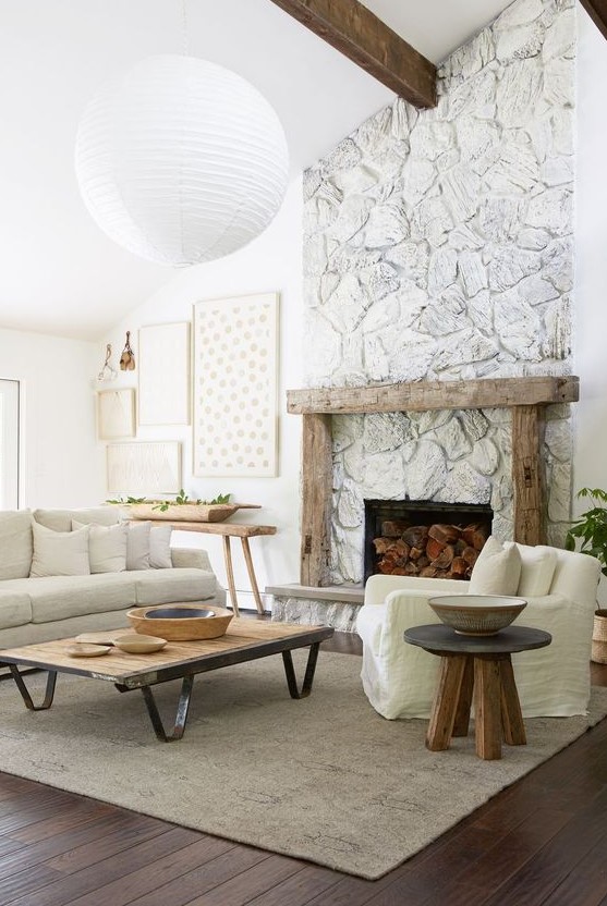 a whimsical, neutral living room with lots of texture, a whitewashed stone fireplace with a rough wood mantel