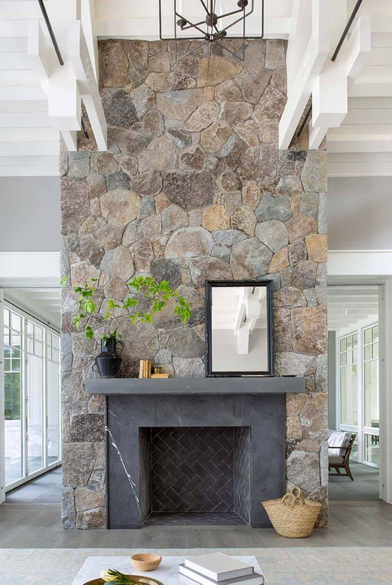 A large stone fireplace, the chimney itself clad in gray marble, is a bold farmhouse piece that adds coziness