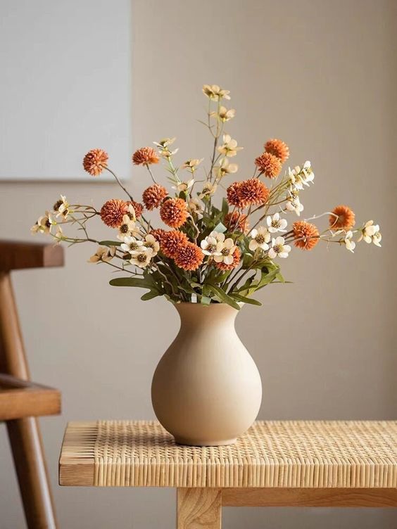 A beautiful fall artificial flower arrangement in rust and white is a perfect decoration for many rooms