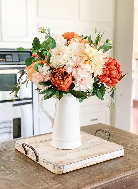 A bold and fun fall faux floral arrangement of neutral, blush and red blooms and greenery is very elegant