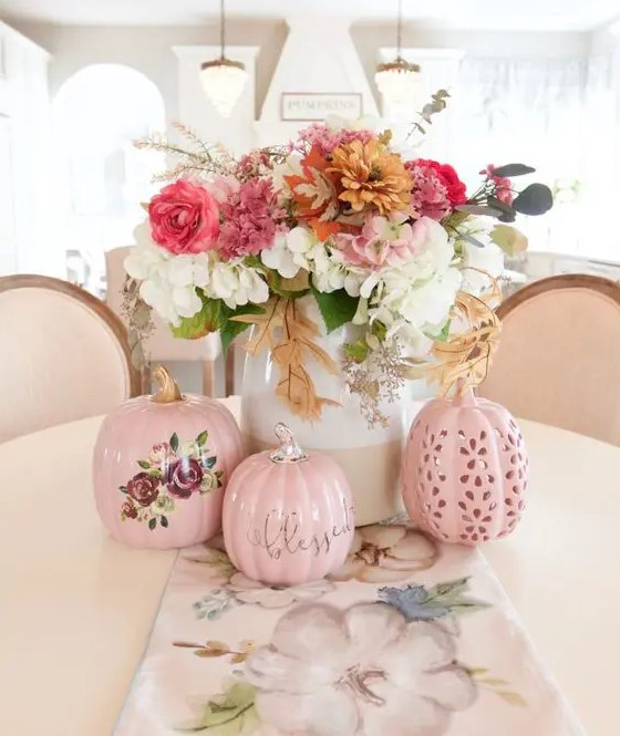 a chic and bright fall floral arrangement of white, pink, rust flowers and greenery as well as pink artificial pumpkins
