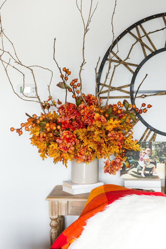A bright artificial flower arrangement in mustard, red and rust with berries and branches is a great idea for fall