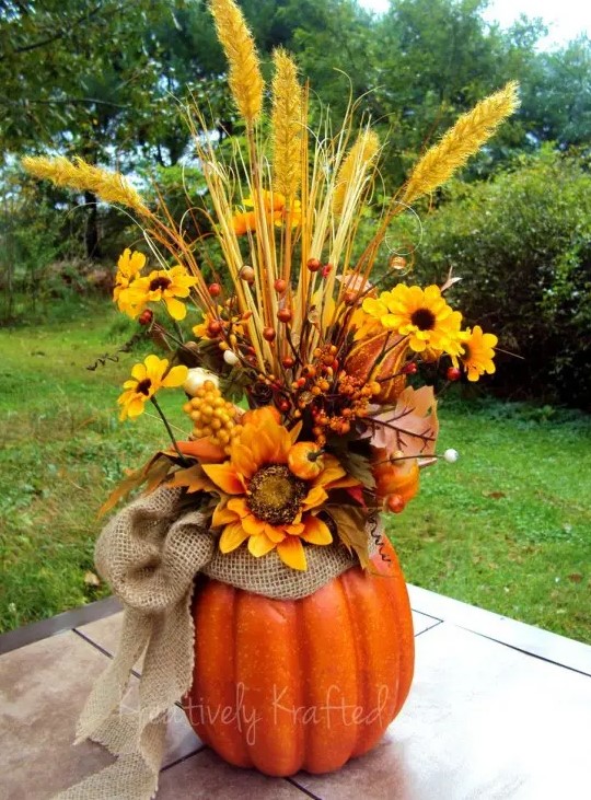 A fall arrangement of faux pumpkins, a burlap bow, bright faux blooms, berries and twigs makes a stylish centerpiece
