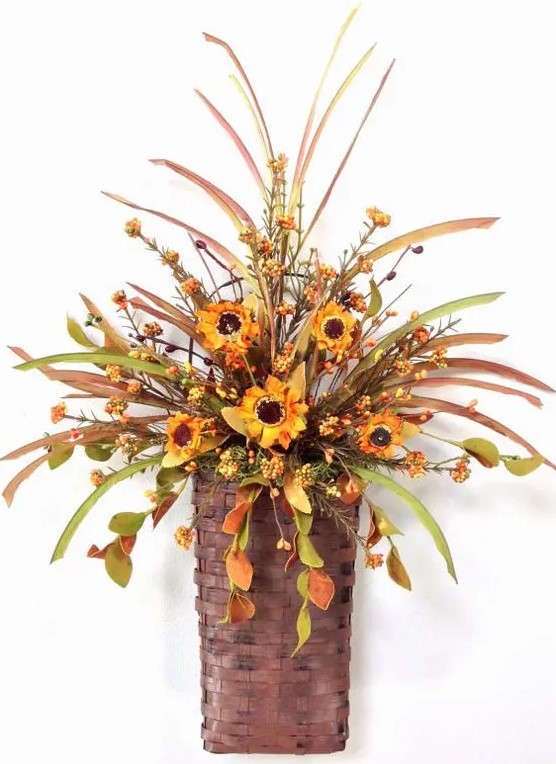 An autumnal arrangement of foliage, berries and bright orange artificial flowers in a basket makes a stylish decoration