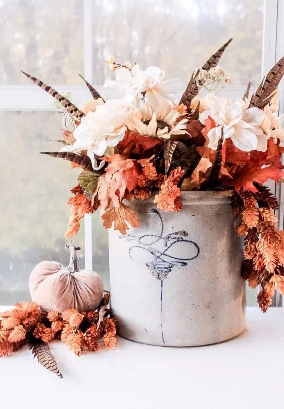 A fantastic fall boho centerpiece of white flowers, fall leaves and feathers in a bucket is a very bold and chic idea