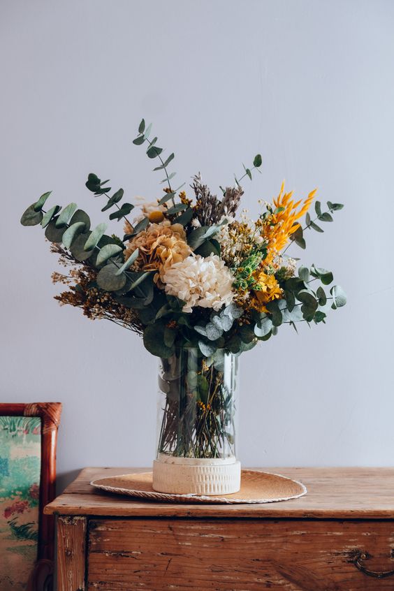 A beautiful autumn flower arrangement made of eucalyptus, dried grasses and some artificial flowers is a lovely idea