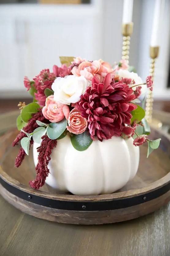 A beautiful Thanksgiving centerpiece with a white pumpkin, white, blush and deep pink flowers and leaves is a great idea