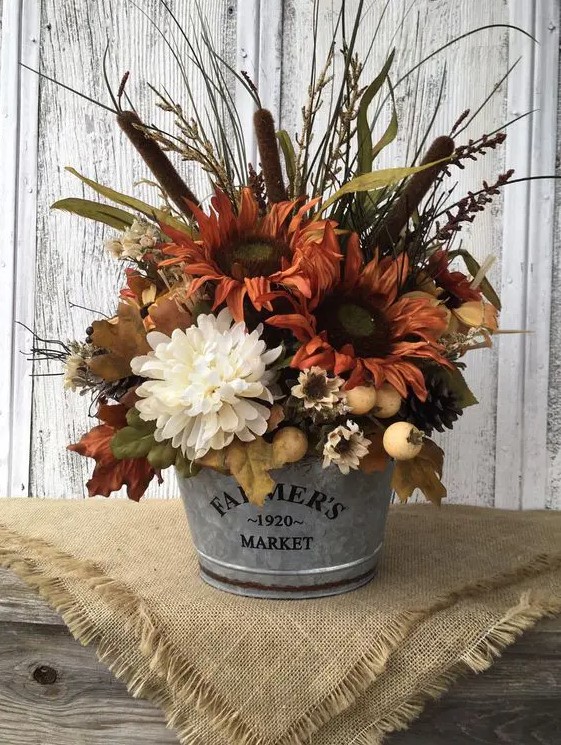 A rustic fall arrangement of rusty and white artificial flowers, berries, grasses, leaves and other things looks very cozy