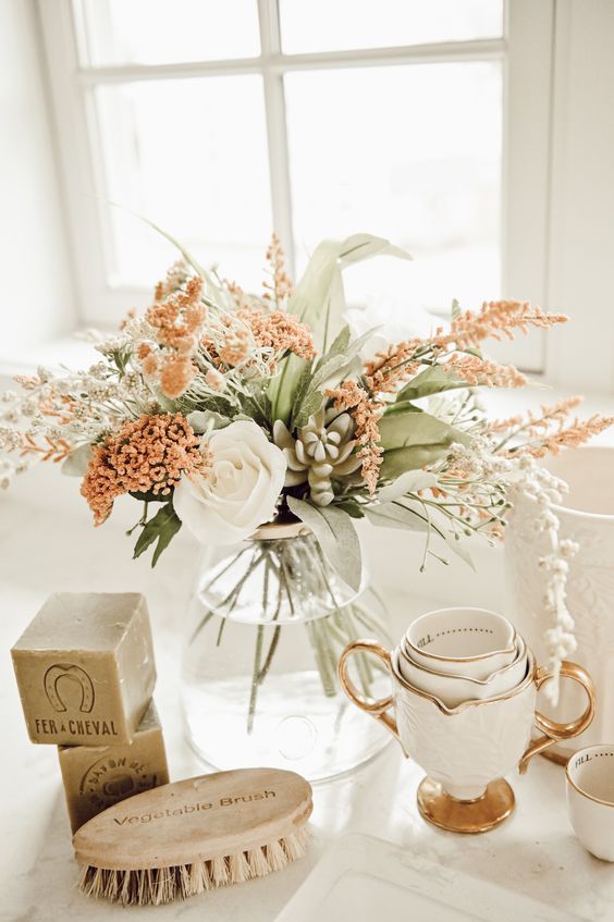 A stylish rust and white faux flower arrangement and some faux leaves are a lovely idea for fall decor