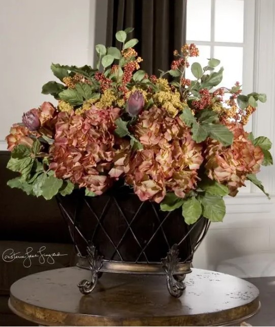 A vintage urn decorated with faux greenery and dried flowers is a sophisticated and chic centerpiece for fall