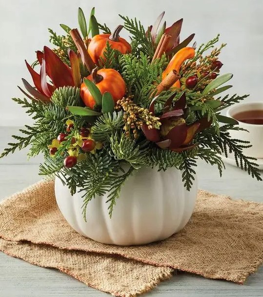 a white pumpkin with artificial flowers, berries, greenery and artificial pumpkins and gourds for fall